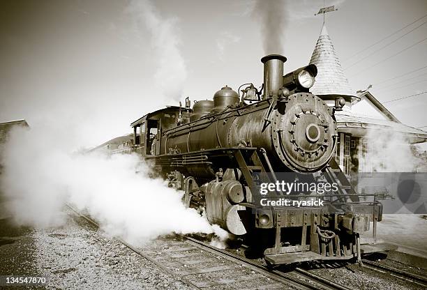 sepia toned vintage steam engine locomotive train leaving station - steam train stock pictures, royalty-free photos & images