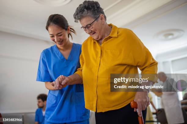 senior woman walking with walking cane with assistance of nurse in nursing home - walking cane 個照片及圖片檔