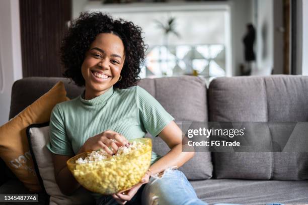 young woman watching tv and eating popcorn at home - point of view - brazil girls supporters stock pictures, royalty-free photos & images