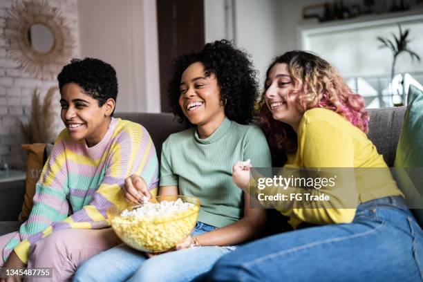 friends watching tv and eating popcorn at home - brazil girls supporters stock pictures, royalty-free photos & images