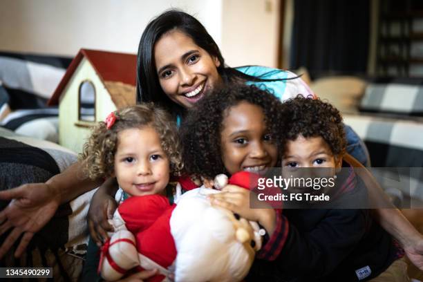 ritratto di una madre e dei bambini con una bambola di babbo natale a casa - family with three children foto e immagini stock