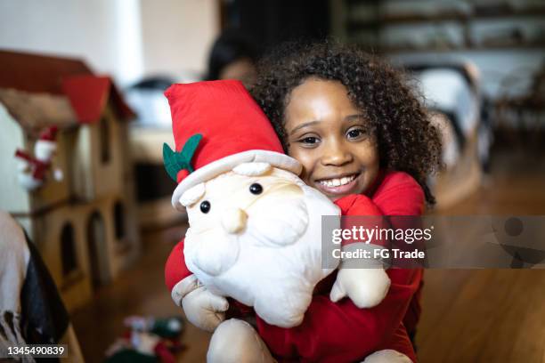 porträt eines mädchens mit einer weihnachtsmannpuppe zu hause - african american christmas images stock-fotos und bilder