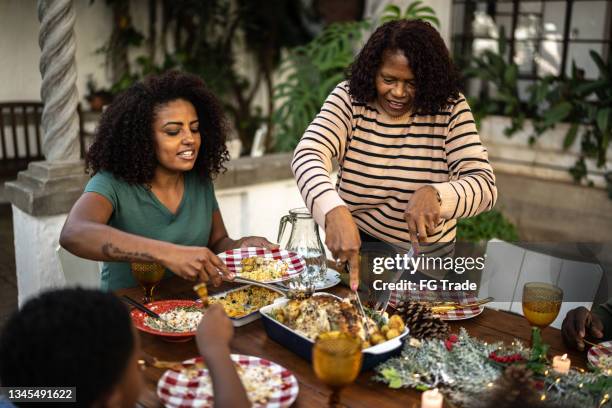 großmutter serviert der familie während des weihnachtsessens essen im freien zu hause - chrismas brasil stock-fotos und bilder