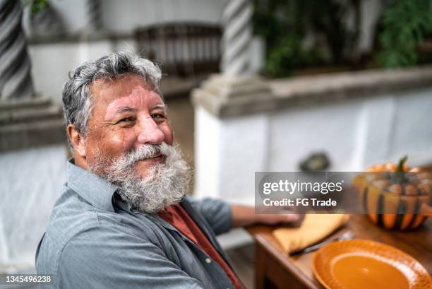 portrait of a senior man with vitiligo sitting on the table at home - vitiligo stock pictures, royalty-free photos & images