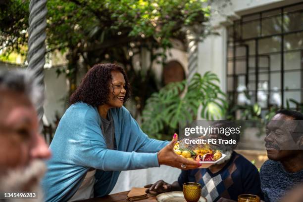 senior woman serving thanksgiving turkey at home - thanksgiving arrival stock pictures, royalty-free photos & images