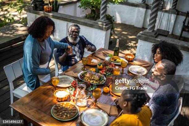 senior woman saying grace before thanksgiving lunch at home - thanksgiving food stockfoto's en -beelden