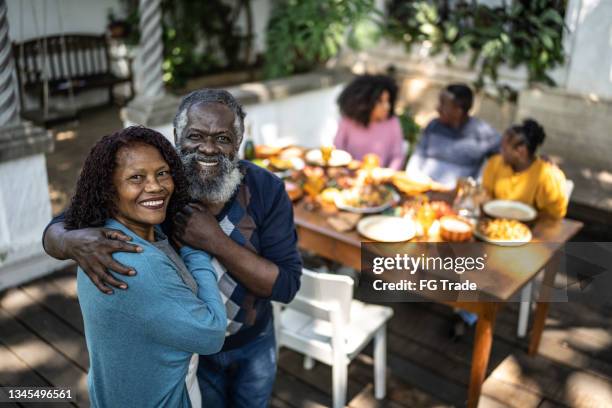 porträt eines älteren paares zu hause mit familienessen im hintergrund - happy anniversary stock-fotos und bilder