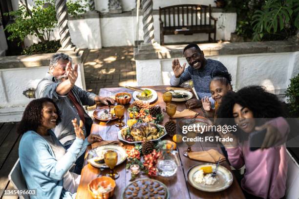 young woman on a video call with the family reunited on the dining table at home - including a young woman with special needs - virtual thanksgiving stock pictures, royalty-free photos & images