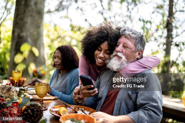 自宅で昼食時に携帯電話でビデオ通話をしている孫娘と祖父 - family and happiness and diverse ストックフォトと画像