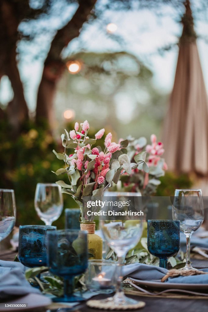 Beautiful Wedding Decoration in turquoise color tones on a dark brown wooden table with selective focus on the dried bouquet