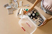 Closeup female hand placing medicament domestic first aid kit. Storage organization emergency supply