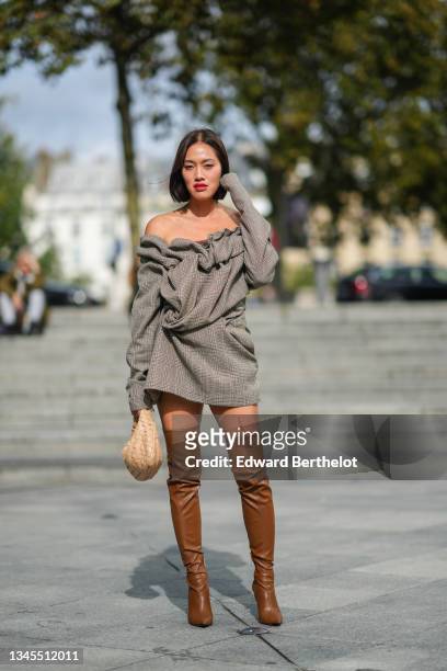Tiffany Hsu wears a gray mini off-shoulder ruffled dress with printed houndstooth patterns, a beige woven leather bag from Bottega Veneta, thigh high...