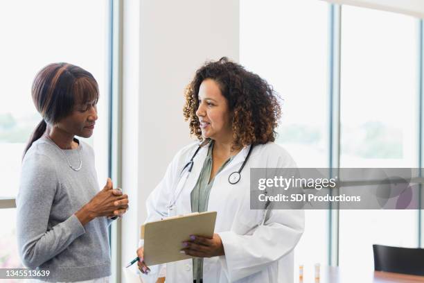 medico di sesso femminile e paziente senior discutono le cartelle cliniche - adult patient with doctor and stethoscope foto e immagini stock