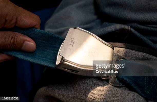 close-up of passenger fixing seat belt on airplane seat - fastening stock-fotos und bilder