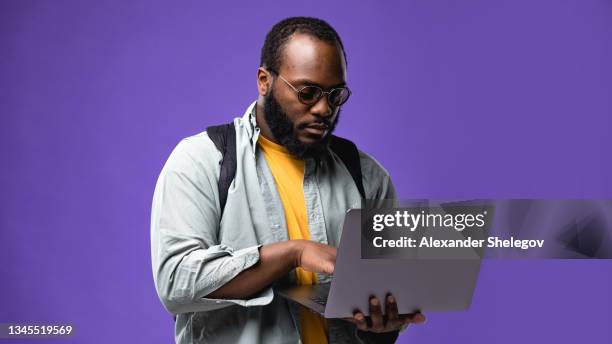 portrait of beard african american freelancer with gray laptop in studio on color background - man white background stock pictures, royalty-free photos & images