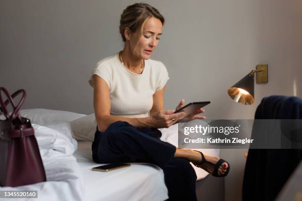 businesswoman sitting on hotel bed, using digital tablet - woman elegant crossed legs stock pictures, royalty-free photos & images