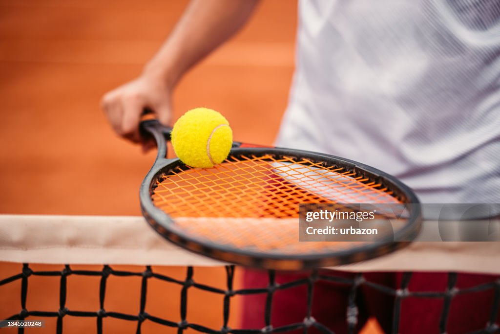 Unrecognizable man holding ball on tennis racket