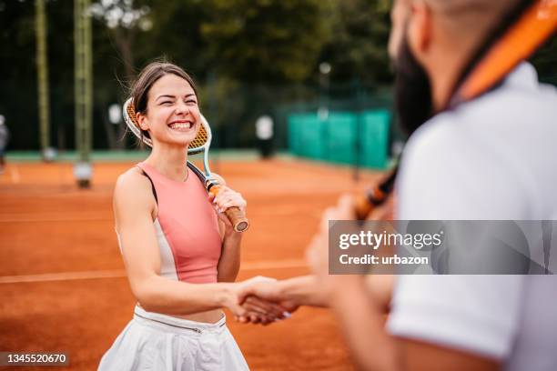 tennisspieler schütteln hände über tennisnetz - tennisplatz stock-fotos und bilder