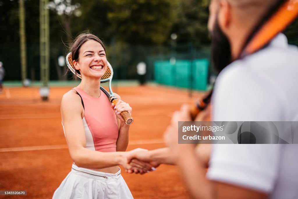 Tennis players shaking hands over tennis net