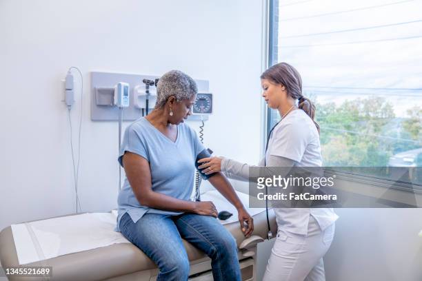 doctor taking senior patients blood pressure - high blood pressure stock pictures, royalty-free photos & images