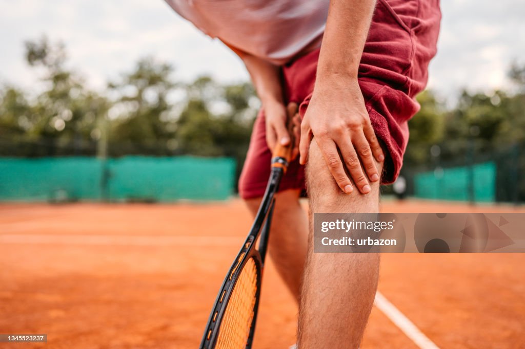 Man suffering from knee pain while playing tennis