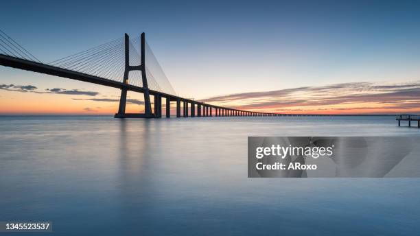 the vasco da gama bridge crosses the tagus river, and is one of the longest bridges in the world. lisbon is an amazing tourist destination because their urban landscapes, by its light, its monuments. - vasco da gama 個照片及圖片檔