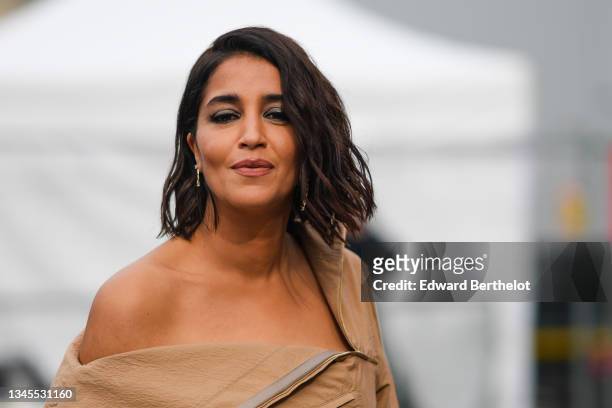 Leïla Bekhti wears a beige oversized one-shoulder shirt with long flared sleeves, outside L'Oreal, during Paris Fashion Week - Womenswear Spring...
