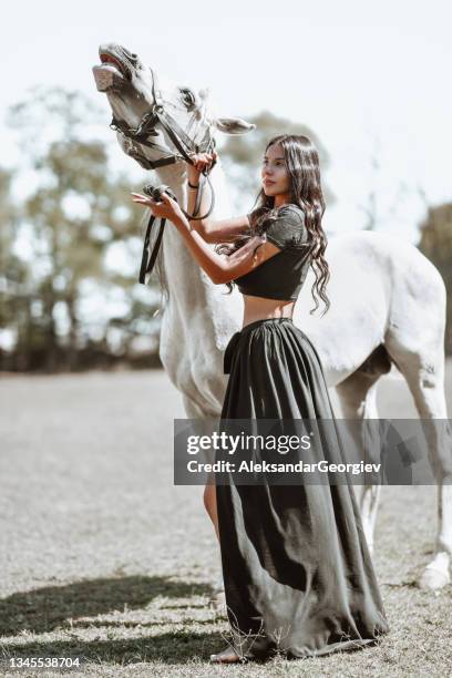 beautiful nomadic gypsy female enjoying time spent with white horse on ranch - gipsy stock pictures, royalty-free photos & images