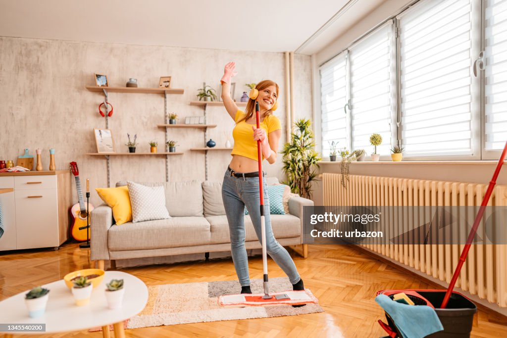 Fröhliche Frau putzt Haus und singt