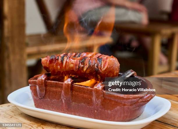 Black Pork Chouriço from Alentejo Region is partially sliced and flame-cooked over alcohol in a terracotta grill at Casa do Alentejo Tabern on...