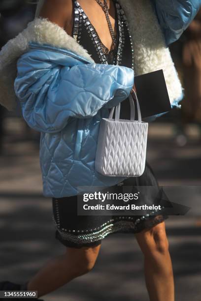 Vanessa Hong wears a large silver chain necklace, a black V-neck with embroidered crystal borders slit / split dress from Miu Miu, a pale blue...