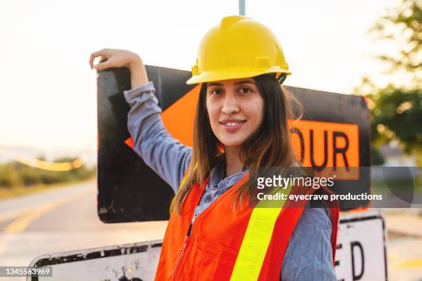 smiling hispanic workers setting barriers and directing traffic street road and highway construction photo series - work crew stock pictures, royalty-free photos & images