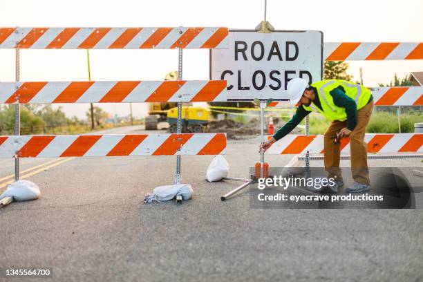 hispanic workers setting barriers and directing traffic street road and highway construction photo series - road construction safety stock pictures, royalty-free photos & images