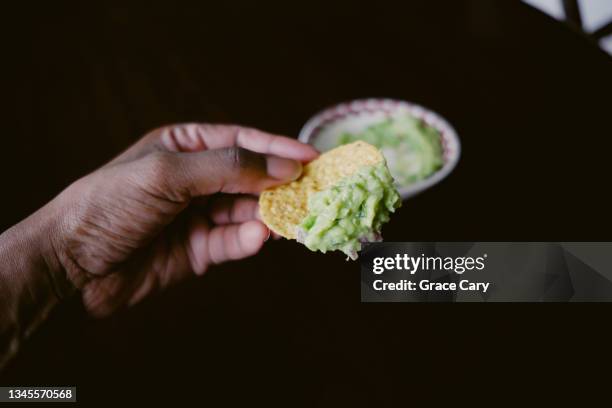 woman snacks on corn chips and homemade guacamole - dippen stock-fotos und bilder