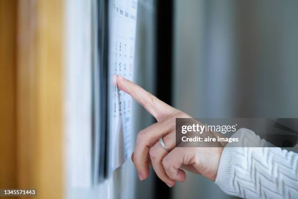 a woman's hand with a wedding ring points with her finger to a date on a cardboard calendar. a woman points to a calendar's day - agenda 個照片及圖片檔