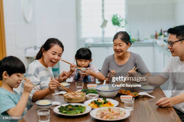 asiatische chinesische familie mit mehreren generationen, die zu hause zusammen zu mittag essen - familie zuhause essen stock-fotos und bilder