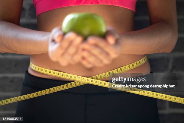 young woman holding measure tape and apple. weight loss. - waist stockfoto's en -beelden