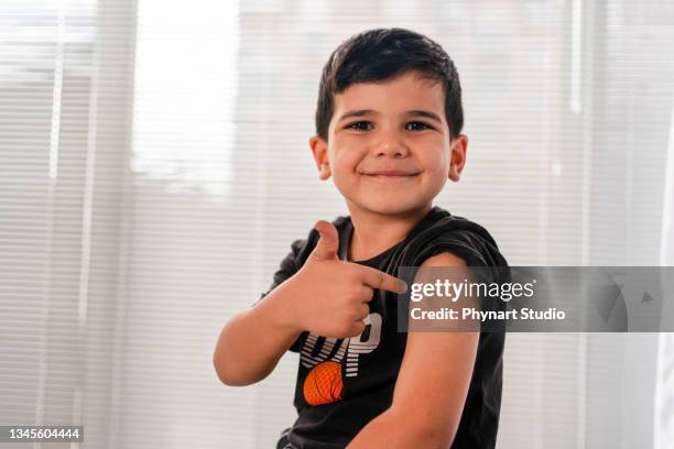 niño vacunado que muestra hombro después de la inyección - medicina preventiva fotografías e imágenes de stock