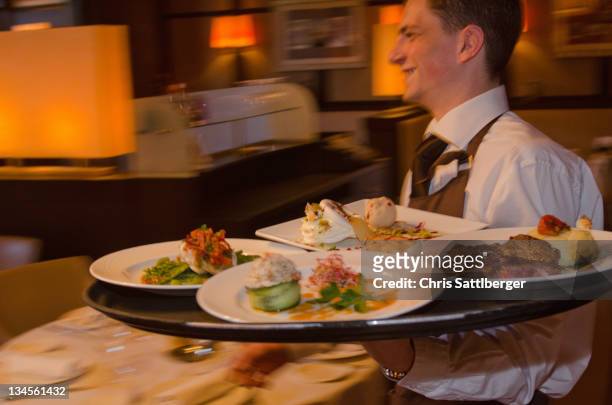 waiter carrying tray with dishes through resturant - paris restaurant stock pictures, royalty-free photos & images