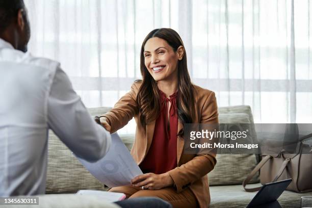 businesswoman shaking hands with coworker in hotel - businessman and businesswoman shaking hands stock pictures, royalty-free photos & images