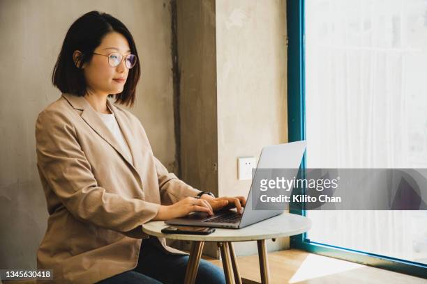 asian businesswoman using a laptop at a cafe - writing email stock pictures, royalty-free photos & images