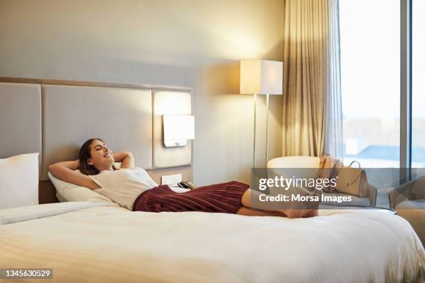businesswoman relaxing on bed in hotel room - habitación de hotel fotografías e imágenes de stock