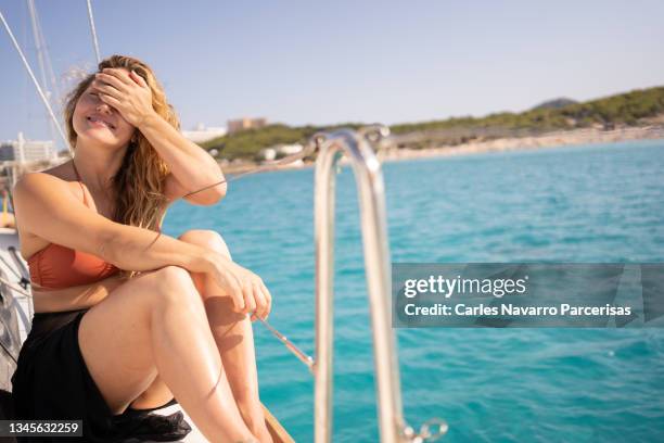 woman covering the face from the sun and sitting on the deck of a sailing boat - blocking sun stock pictures, royalty-free photos & images