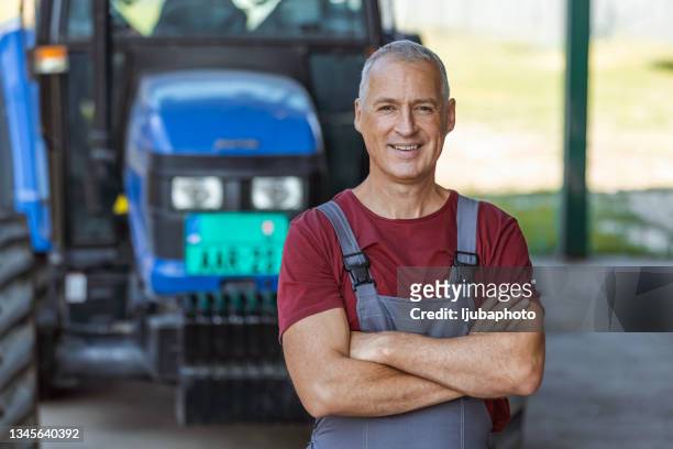 un propriétaire confiant posant près d’un tracteur à l’extérieur - harvesting stock photos et images de collection