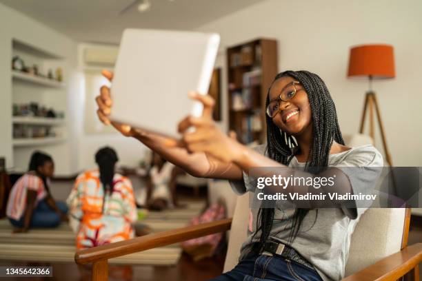 holding an ipad in the air and smiling - braided hairstyles for african american girls stock pictures, royalty-free photos & images
