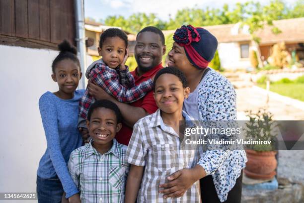 a family of three sons and one daughter stand posing for a photo outside of their house - jamaicansk stock pictures, royalty-free photos & images
