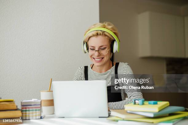 young woman in green headphones working on laptop. - dumb blonde stock pictures, royalty-free photos & images