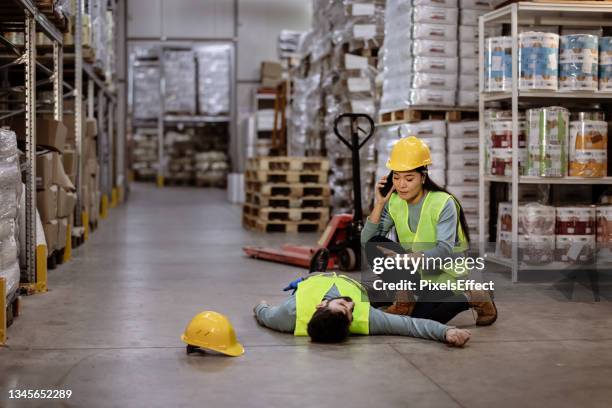 lavoratore chiama un'ambulanza dopo che il responsabile del magazzino si è sdraiato sul pavimento del magazzino - accidents and disasters foto e immagini stock