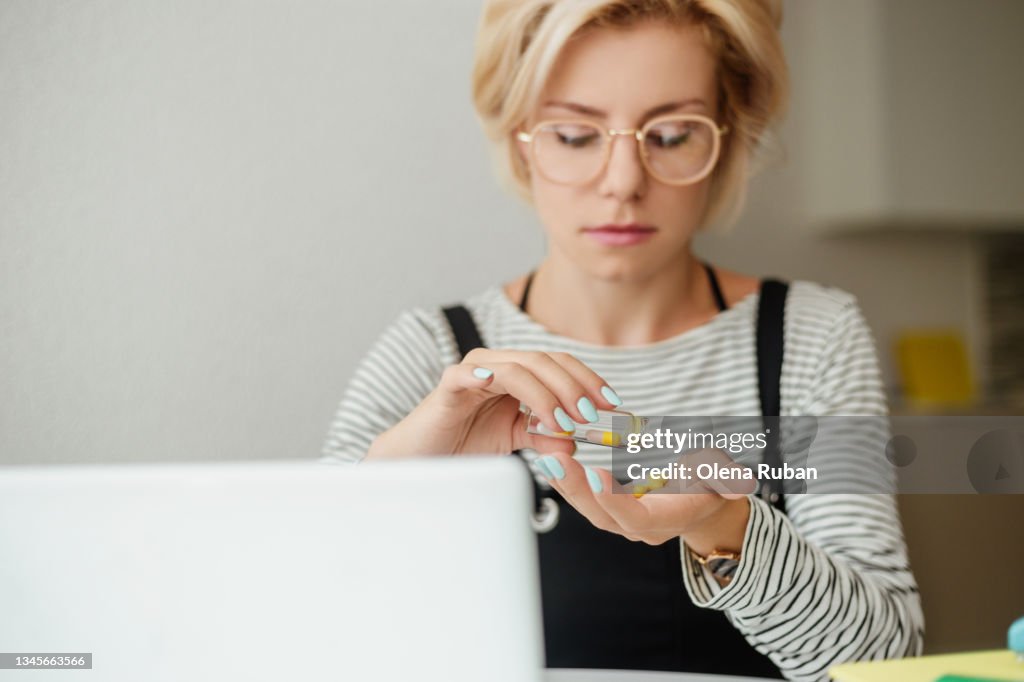 Young woman pouring out pills on hand.