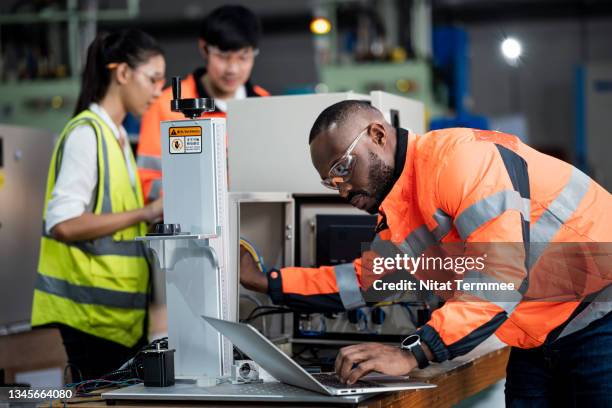 mechanical and electrical engineers in renewable energy industry. multiracial group of electrical engineers is working in a power storage room while testing voltage of solar cell storage batteries. - battery power stockfoto's en -beelden